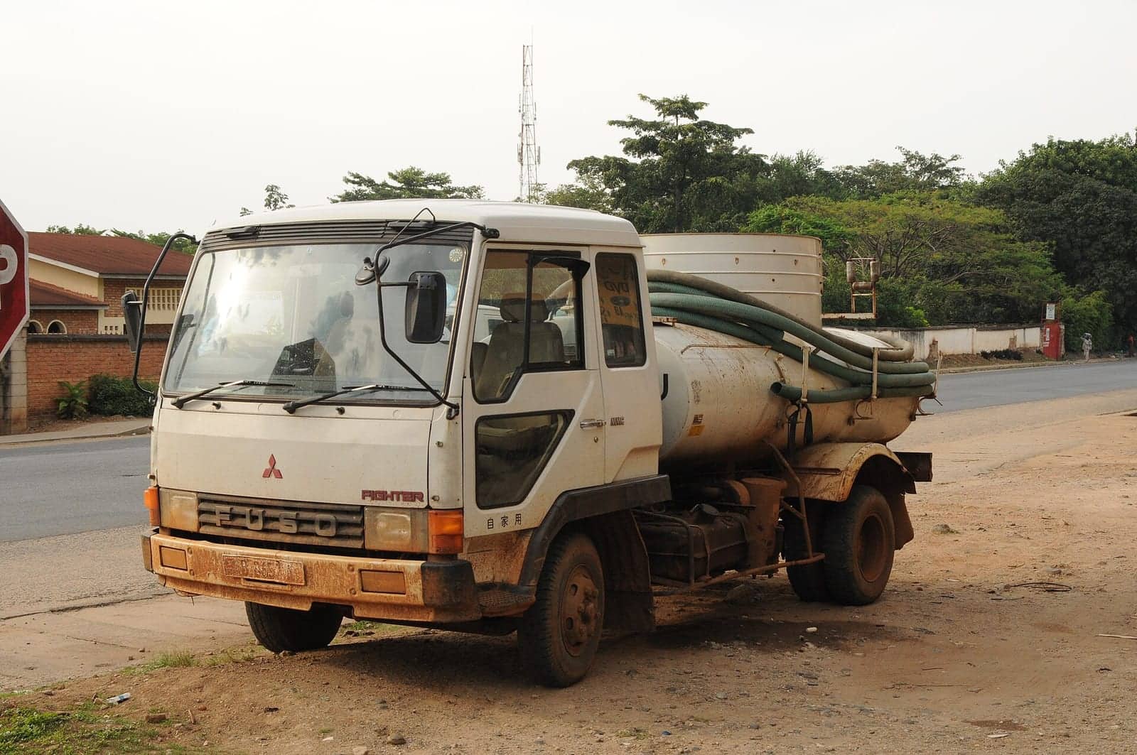Unbranded vacuum tanker with suction hoses used for septic waste collection